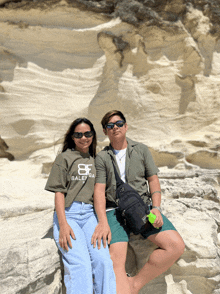 a man and a woman are sitting on a rock wearing balenciaga shirts