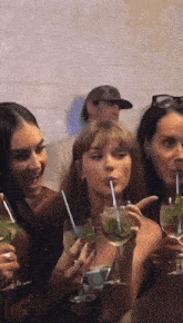 a group of women sitting at a table drinking from glasses