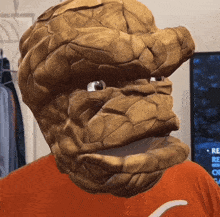 a man wearing a mask that looks like the thing is wearing an orange shirt