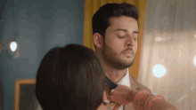a woman adjusts a man 's tie while he looks at her
