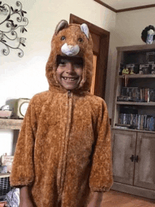 a young boy is wearing a teddy bear costume and smiling .