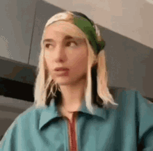 a woman with blonde hair wearing a blue jacket and a green headband .