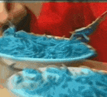 a person is eating a plate of blue spaghetti