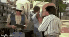 a man in a striped shirt is talking to another man in a striped vest .