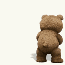 a brown teddy bear is holding a bottle in his hand