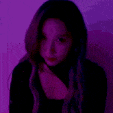 a close up of a woman 's face with a purple background and a black top .