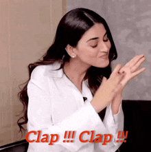 a woman in a white shirt is clapping her hands with the words clap !!! clap !!! behind her