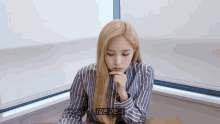 a woman in a striped shirt is sitting at a table with her eyes closed