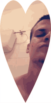 a man taking a selfie in a heart shaped mirror