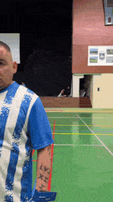a man in a blue and white striped shirt has a tattoo on his arm that says lvi x h