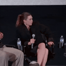 a woman is sitting in a chair with a microphone in her hand .