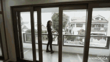 a woman is standing in front of a sliding glass door that says made in animotica