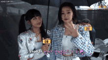 two girls standing next to each other holding an umbrella with a yellow label that says honeycam.org on it