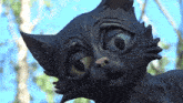 a close up of a statue of a cat with a blue sky in the background