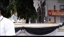 a man stands in front of a building with a sign that says วัด เขียน