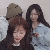 a group of young women are sitting next to each other . one of the girls is wearing a beanie .