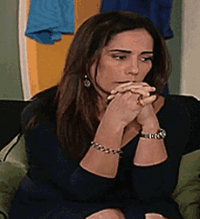 a woman wearing a watch and a bracelet is sitting on a couch