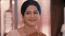 a close up of a woman wearing a sari and a necklace smiling .