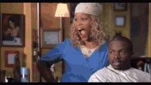 a woman is standing next to a man in a barber shop and making a funny face .