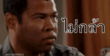 a man is sweating profusely and looking at the camera with a foreign language written on his face .