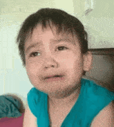 a little boy is crying and making a funny face while wearing a blue shirt .