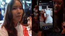 a woman is holding a cell phone with a picture of two alpacas on the screen