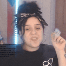 a woman with a bandana on her head is holding a piece of paper in front of her face