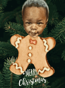 a gingerbread man ornament with a baby 's face and the words merry christmas on it