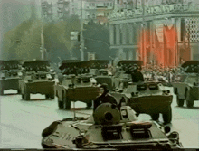 a group of military vehicles are driving down a street in a parade .