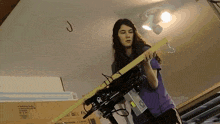 a woman in a purple shirt holds a piece of wood in front of a cardboard box that says " fragile "