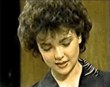 a woman with curly hair is wearing a black and white striped shirt .