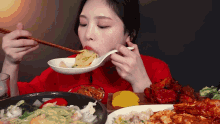 a woman in a red shirt is eating noodles with chopsticks .