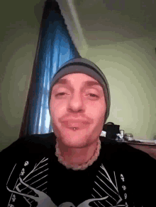a man wearing a hat and a black shirt has a piercing in his mouth