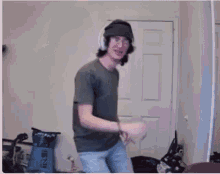 a man wearing headphones and a hat is dancing in a living room .