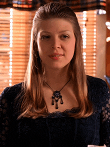 a woman wearing a black lace top and a black necklace smiles for the camera