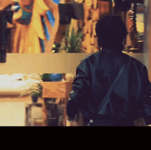 a man in a black jacket is walking in front of a glass wall