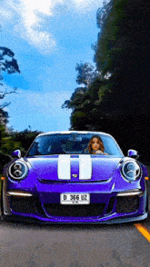 a woman driving a purple sports car with a license plate that says d 366 uz