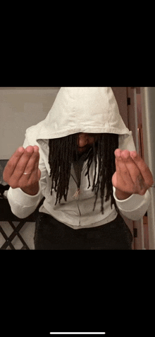 a man with dreadlocks is wearing a white hoodie and giving the middle finger