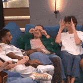 a group of people are sitting on a couch laughing and making funny faces .
