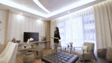a woman is standing in a living room with a television