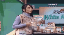 a woman is standing in front of a table with boxes of white koffie