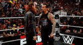 two wrestlers standing in a wrestling ring with a crowd watching