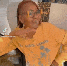 a woman wearing glasses and a yellow sweater with the word laughs on it .