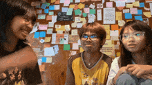 a man and two girls are sitting in front of a wall covered in sticky notes including one that says " i love you "