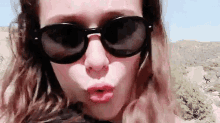 a woman wearing sunglasses and making a kiss with her lips .