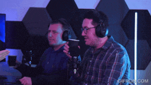 two men wearing headphones are sitting in front of a microphone with gifrun.com in the corner