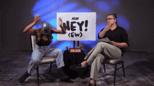 a woman sitting in front of a sign that says hey