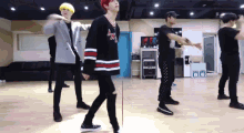 a group of young men are dancing in a room and one of them is wearing a shirt that says ' chicago '