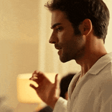 a close up of a man 's face with a beard wearing a white shirt