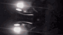 a car 's headlights are reflected in a dark water surface